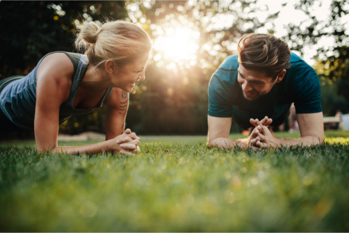 A woman and a man planking on grass